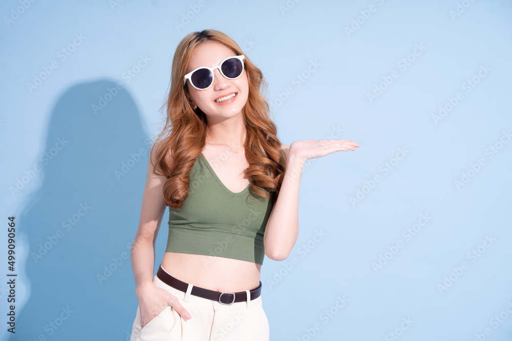 Beautiful young Asian woman on blue background, summer vacation concept