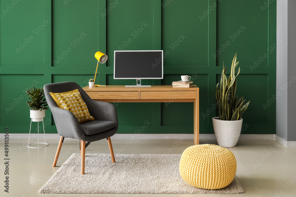 Interior of stylish room with comfortable pouf and modern workplace near color wall