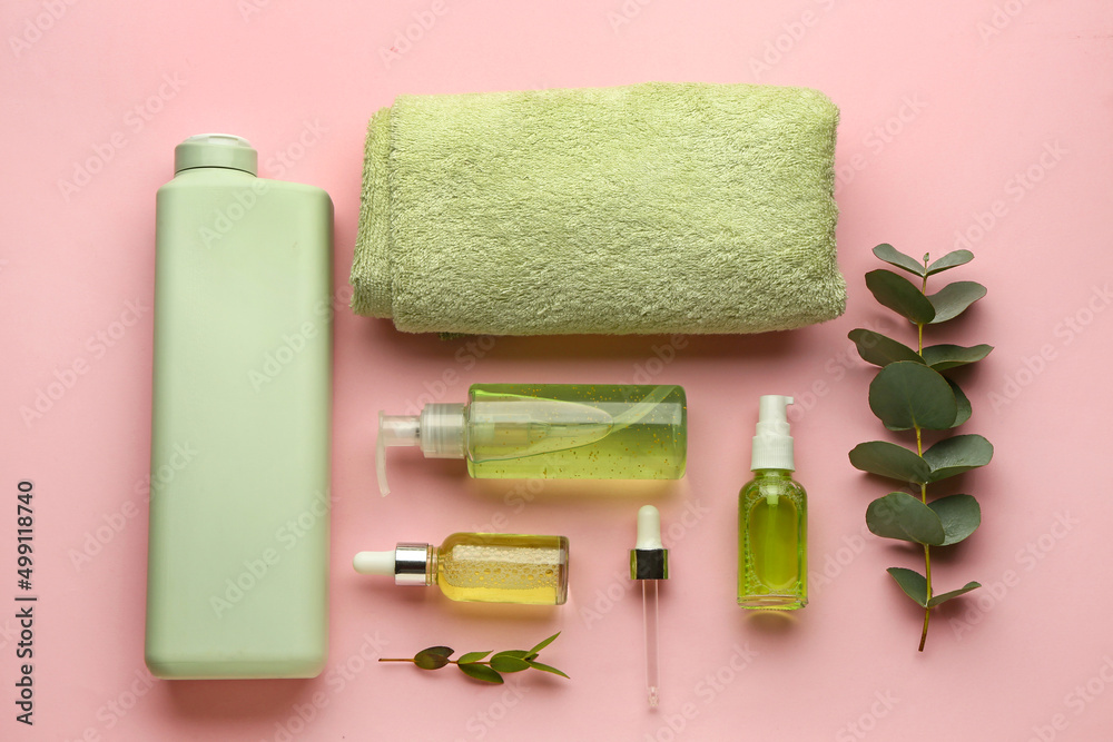 Set of cosmetic products, clean towel and eucalyptus branches on pink background