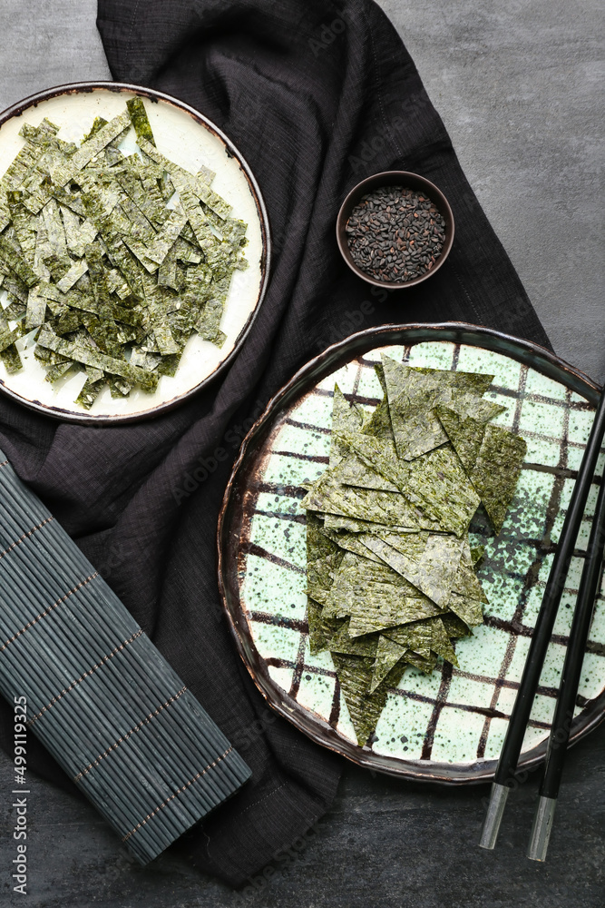 Plates of tasty seaweed sheets on black background