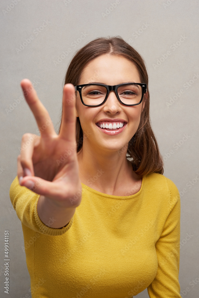 Peace out. Studio portrait of an attractive young woman giving you the peace sign while posing again