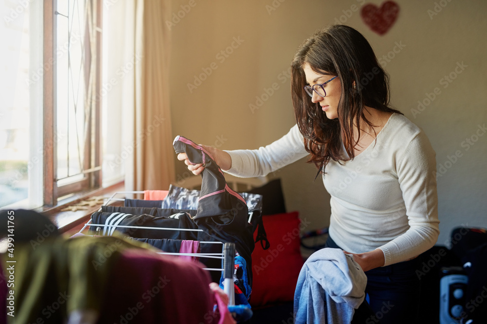 家庭生活。一个年轻女人在家挂衣服的裁剪镜头。