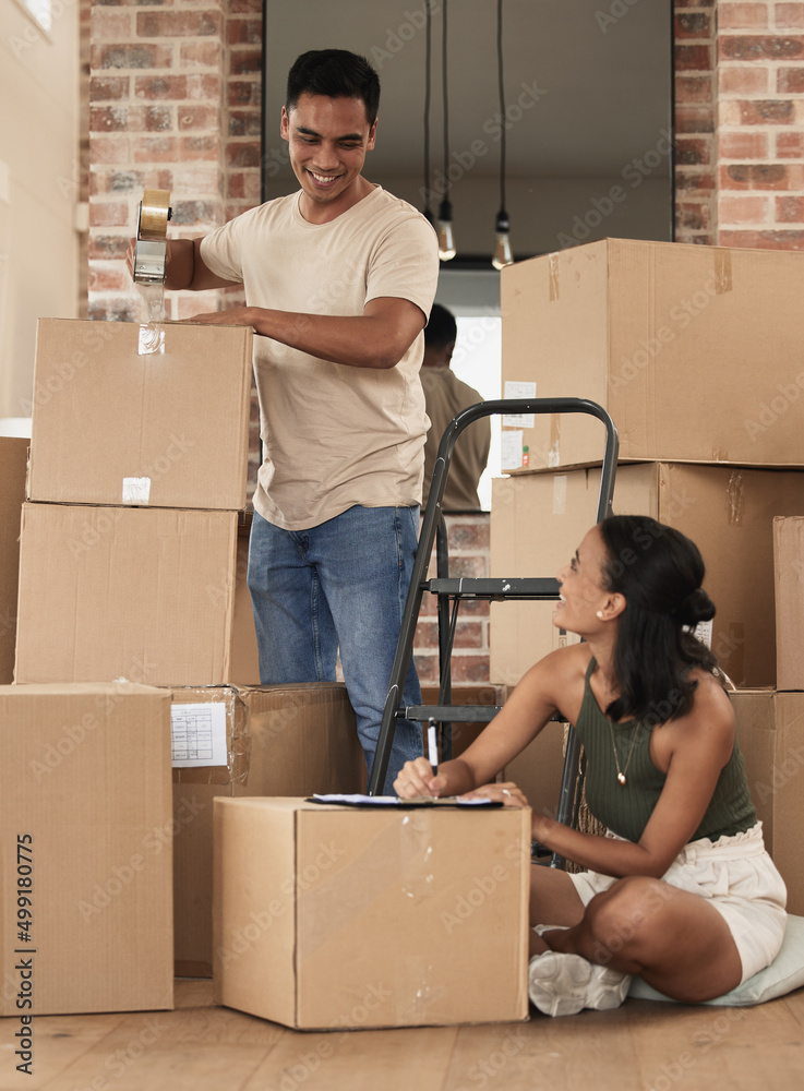 We are most alive when were in love. Shot of a young couple packing up to move in a room at home.