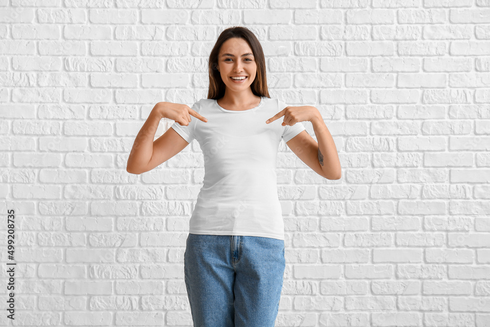 Young woman in blank t-shirt on white brick background