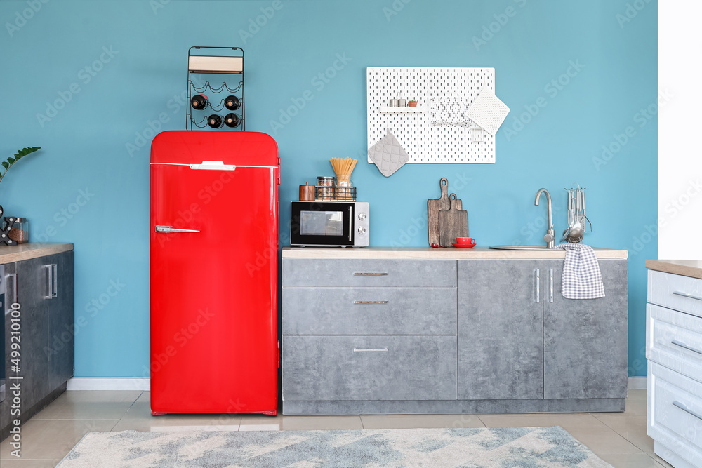 Interior of stylish kitchen with red fridge, counters and pegboard