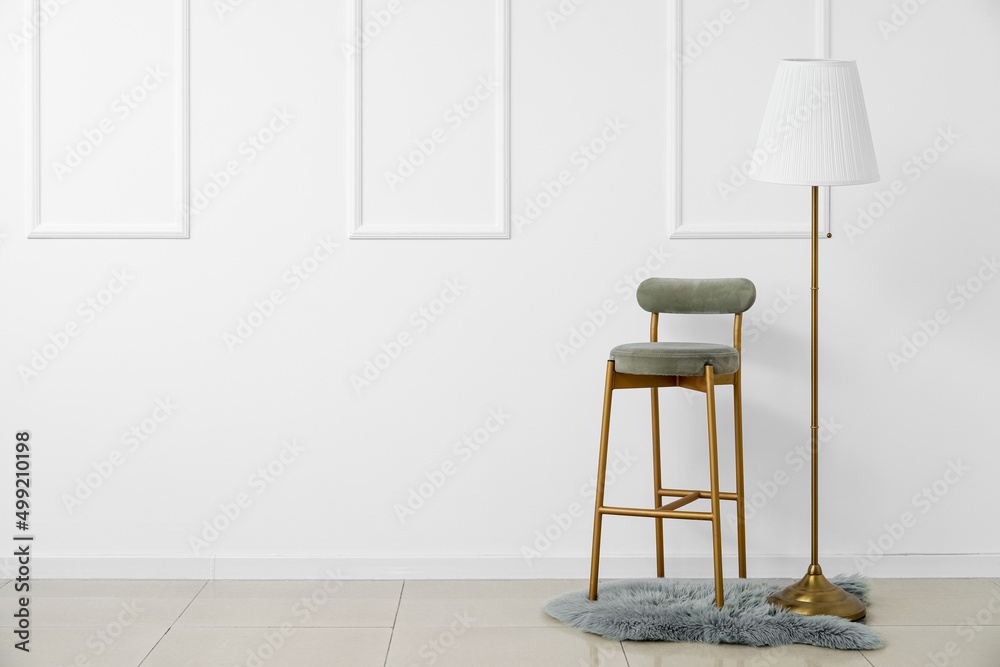 New chair and modern lamp near white wall