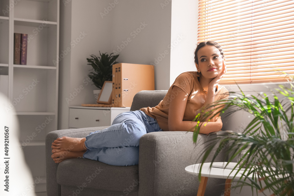 Young barefoot woman resting in armchair at home