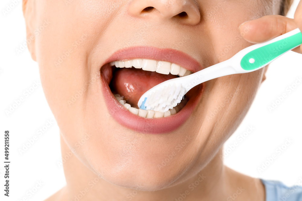 Beautiful mature woman brushing teeth on white background, closeup