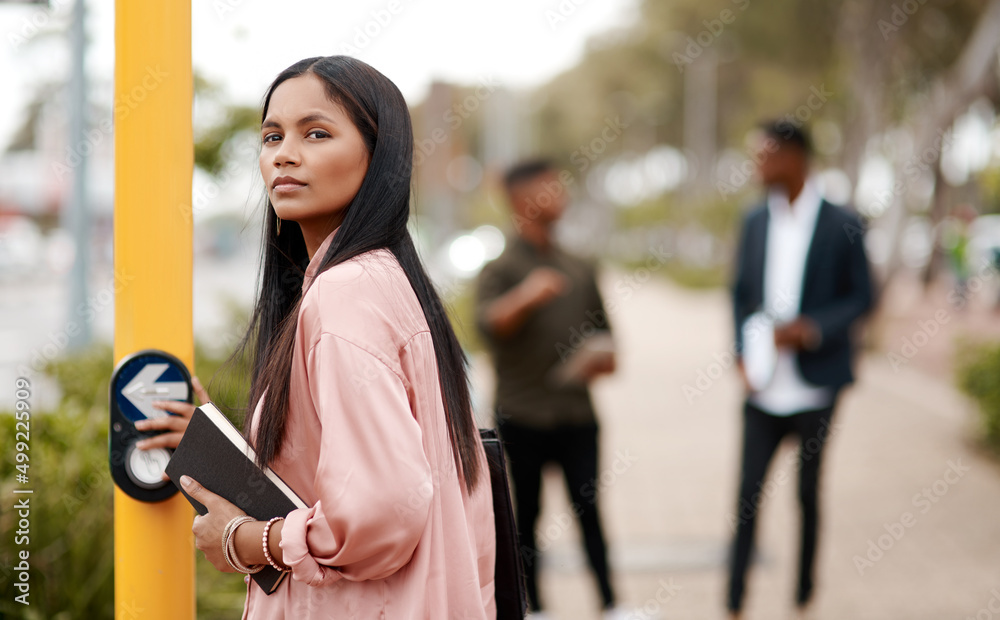 Determination determines your direction. Shot of a young businesswoman about to cross a city street.