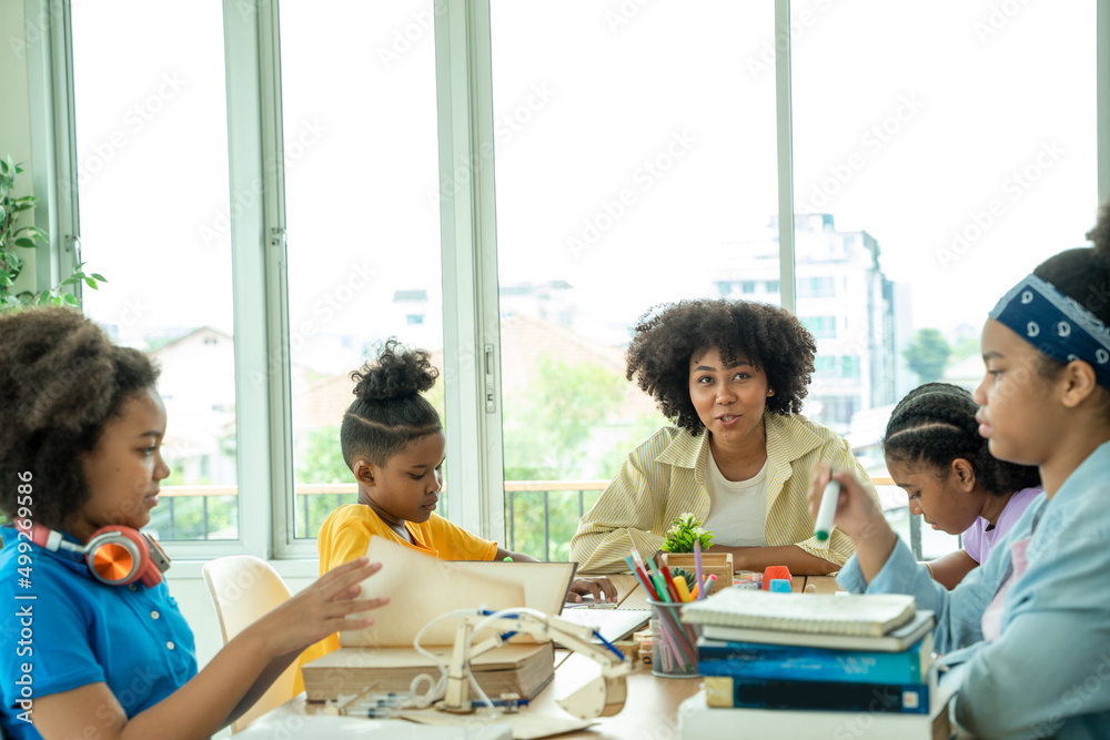 African American girl school children studying together in classroom. Groups of school children work