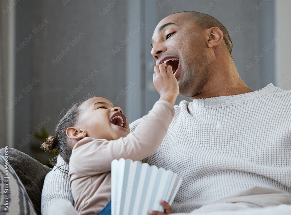 Se might as well be covered in glitter. Shot of a father and daughter eating popcorn while watching 