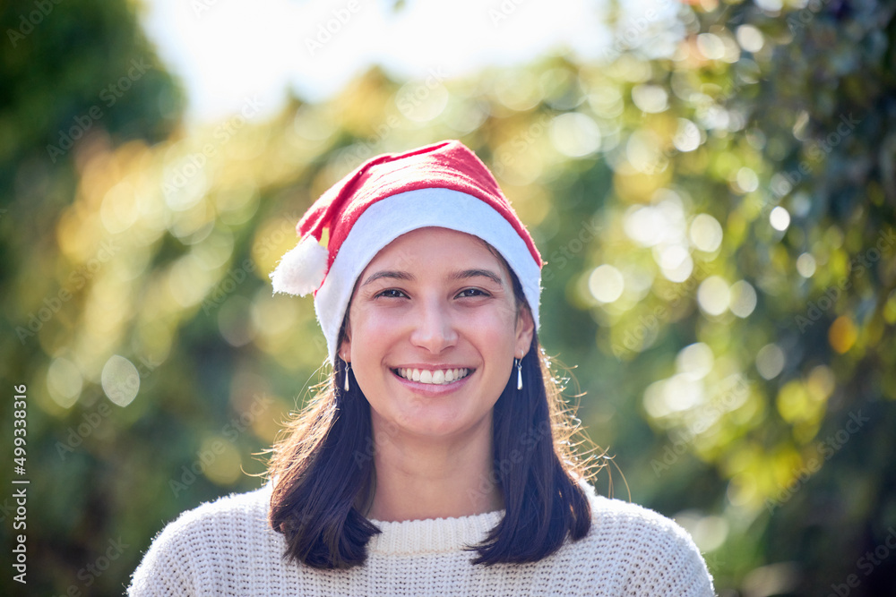 Not every Christmas is covered in snow. Portrait of a young woman celebrating Christmas in a garden.