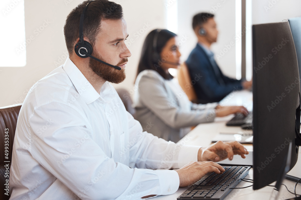 Let me take a deeper look into this. Shot of a young call centre agent working in an office with his