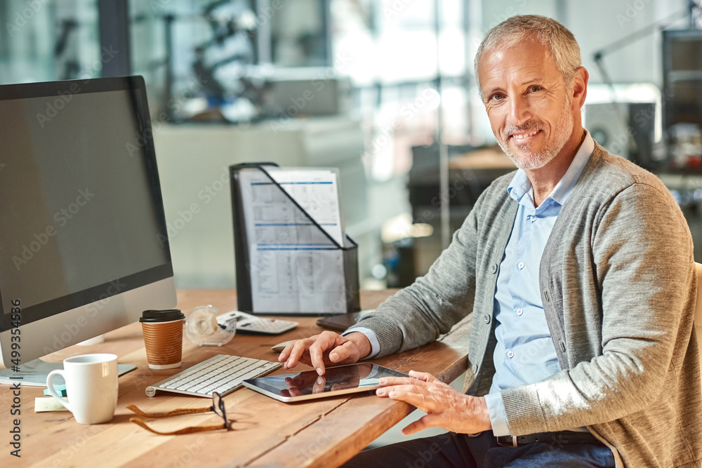 Getting down to work with a smile. Portrait of a smiling mature businessman sitting at his desk in a