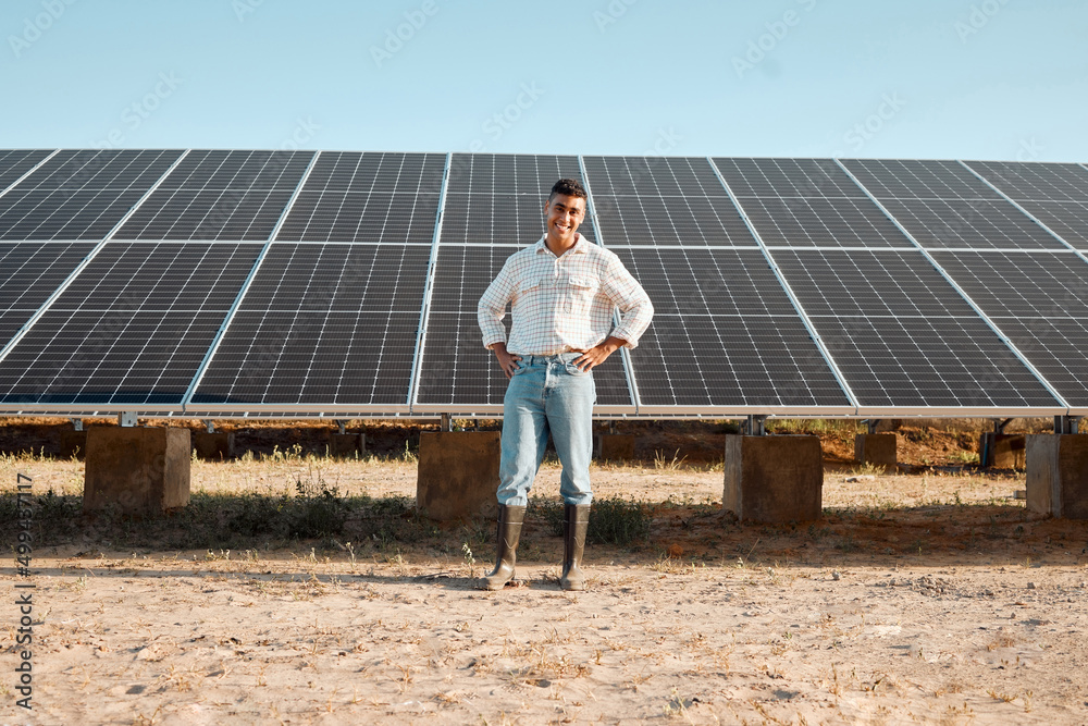 技术让农业变得更容易。一个年轻人站在农场太阳能电池板旁边的照片。