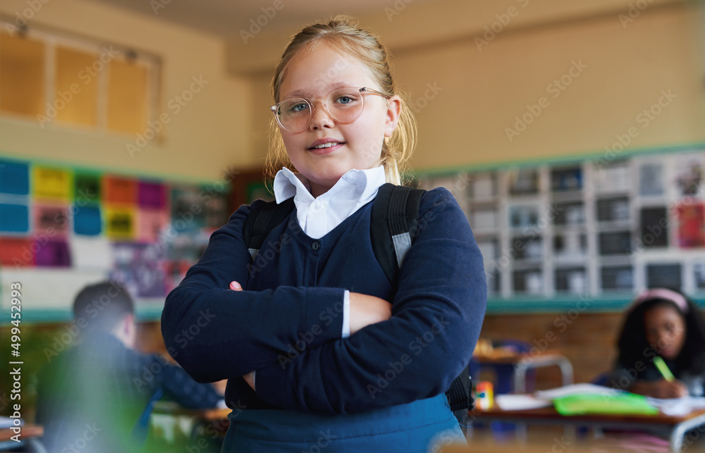 Education is the focus. Shot of a young girl standing in her classroom at school with her arms folde