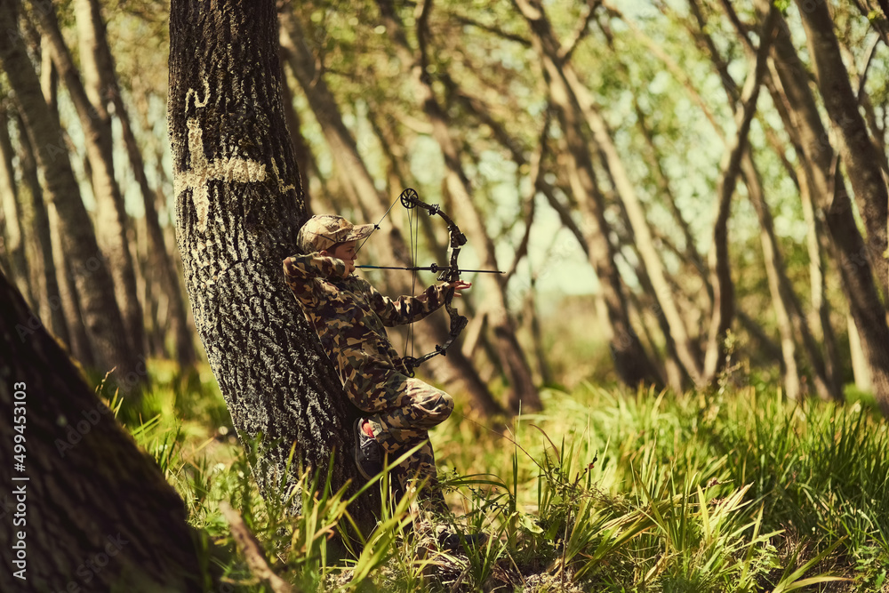 Hes a great little marksman. Shot of a cute little boy in camouflage playing with his bow and arrow 