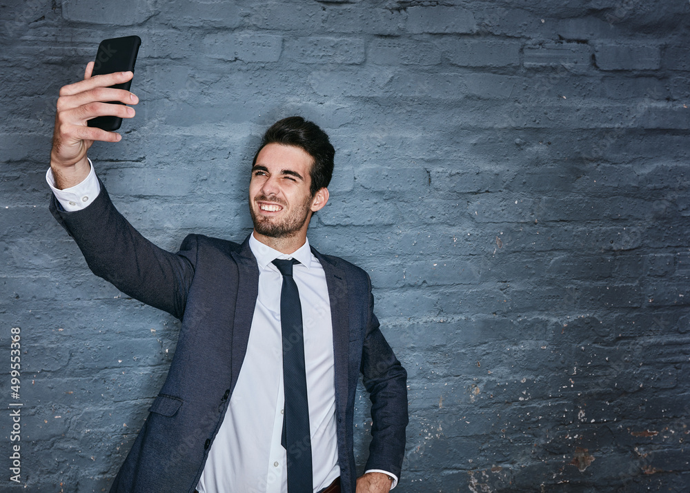 Taking a classy selfie. Shot of a businessman taking a selfie against a grey wall.