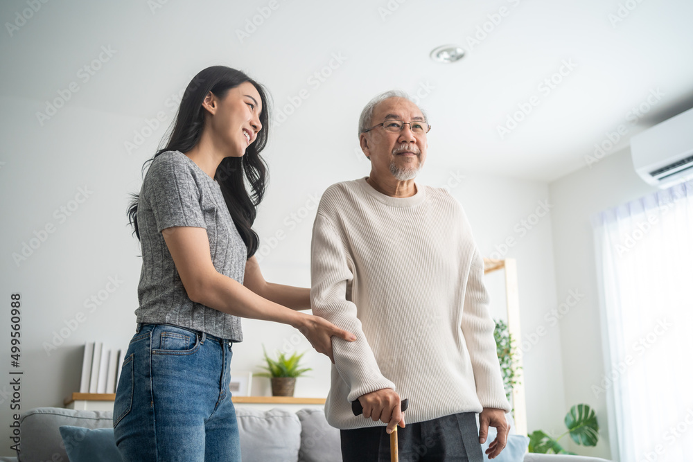 亚洲年轻女儿支持老年男子在家使用助行器行走