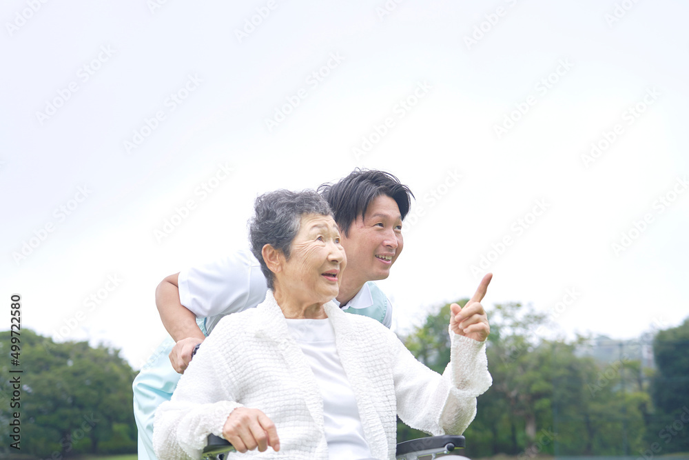 介護士と車椅子に乗った高齢者　屋外