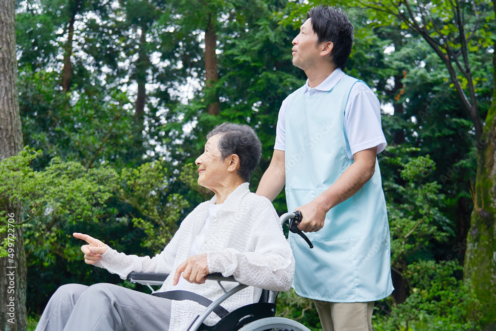 介護士と車椅子に乗った高齢者　屋外