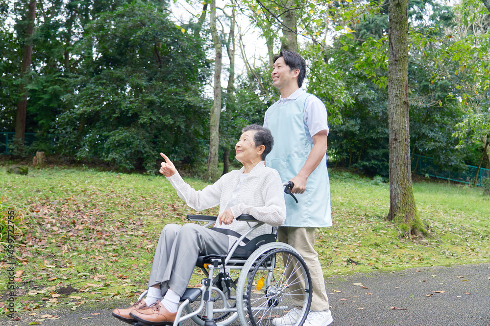 介護士と車椅子に乗った高齢者　屋外