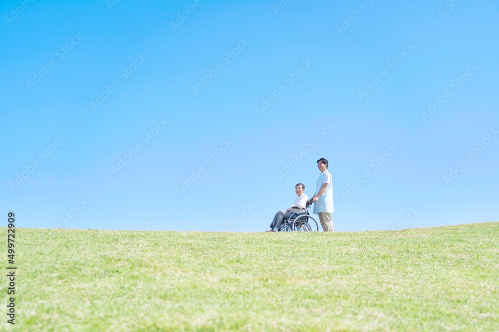 介護士と車椅子に乗った高齢者　屋外