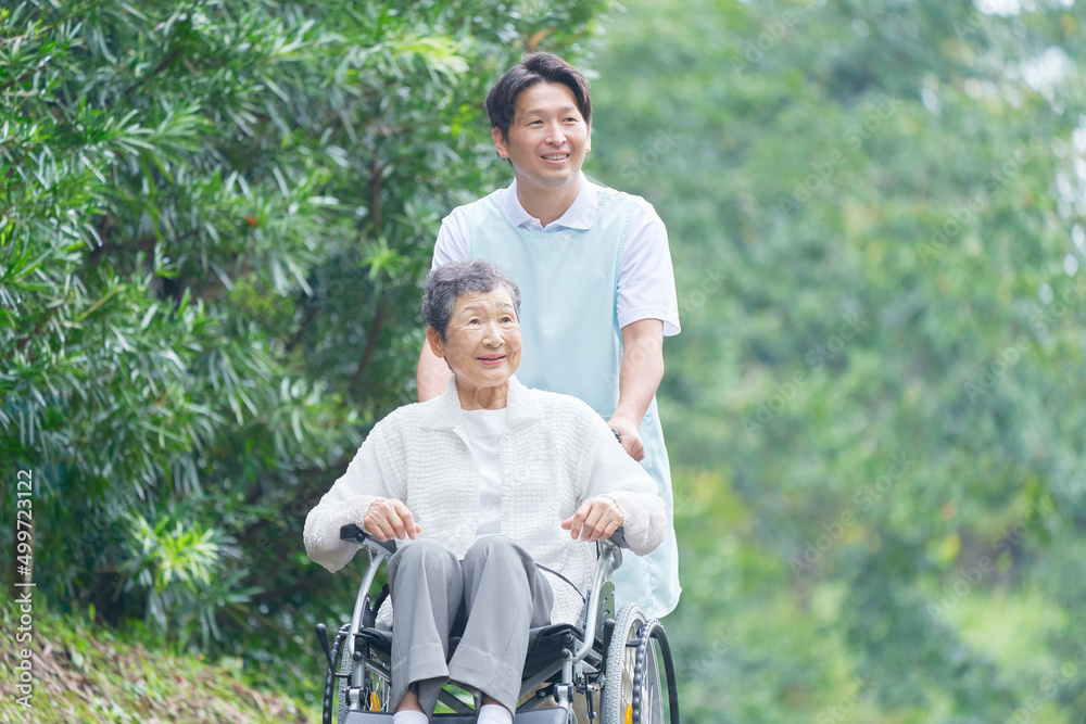 介護士と車椅子に乗った高齢者　屋外