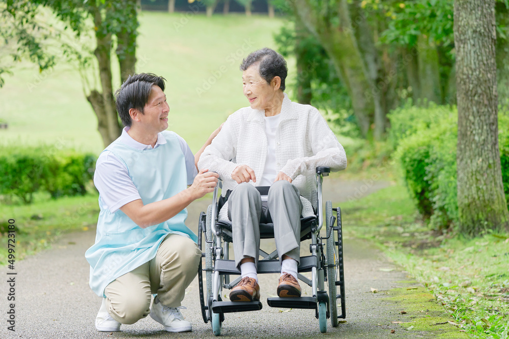 介護士と車椅子に乗った高齢者　屋外