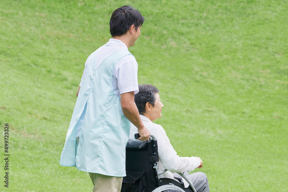 介護士と車椅子に乗った高齢者　屋外