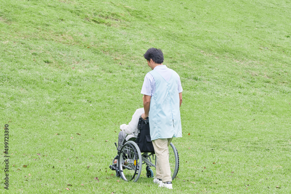 介護士と車椅子に乗った高齢者　屋外