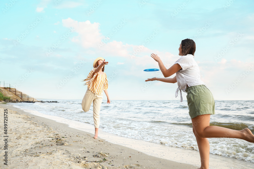 快乐的年轻女子在海边玩飞盘