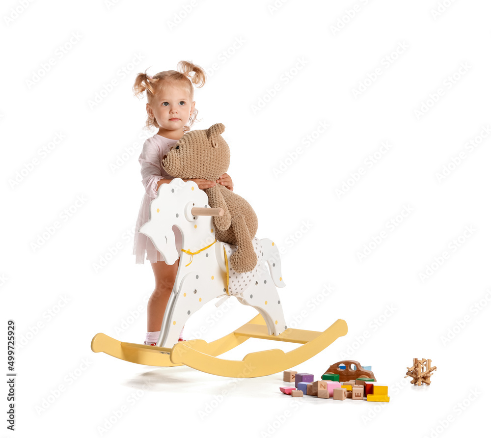 Adorable baby girl with rocking horse and toys on white background