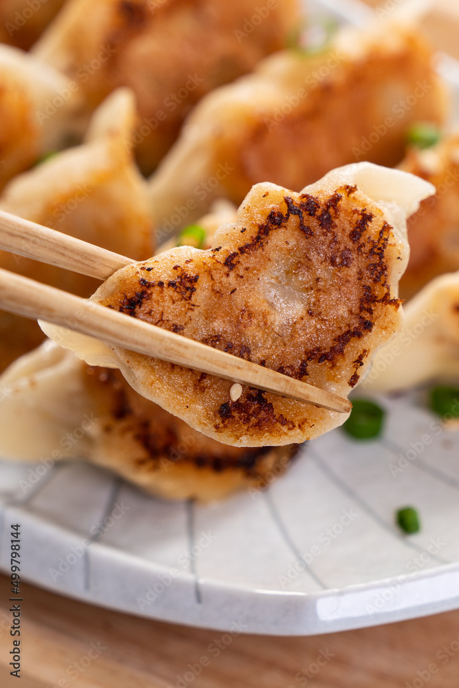 白桌子背景上放着酱油的锅里煎饺子饺子饺子。