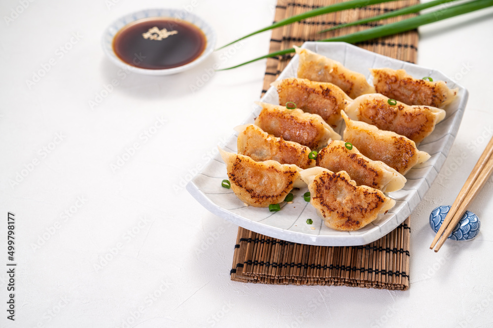 白桌子背景上放着酱油的锅里煎饺子饺子饺子。