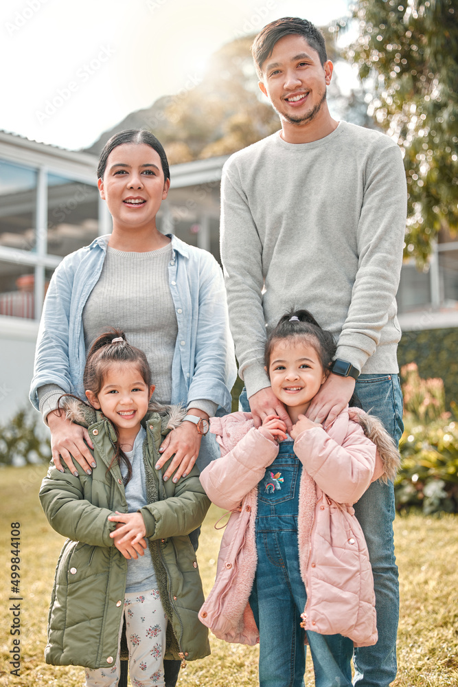 这是我美丽的家庭。一对年轻夫妇和他们的两个女儿站在他们的房子外面的照片