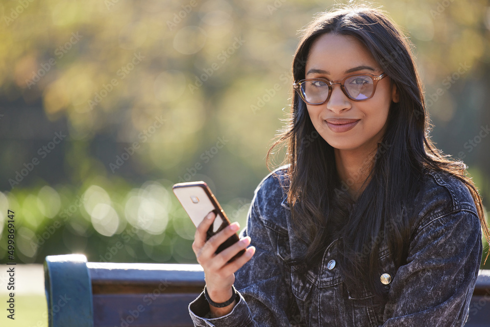 Still warming up to her new surroundings. Shot of a beautiful young student using her phone while si