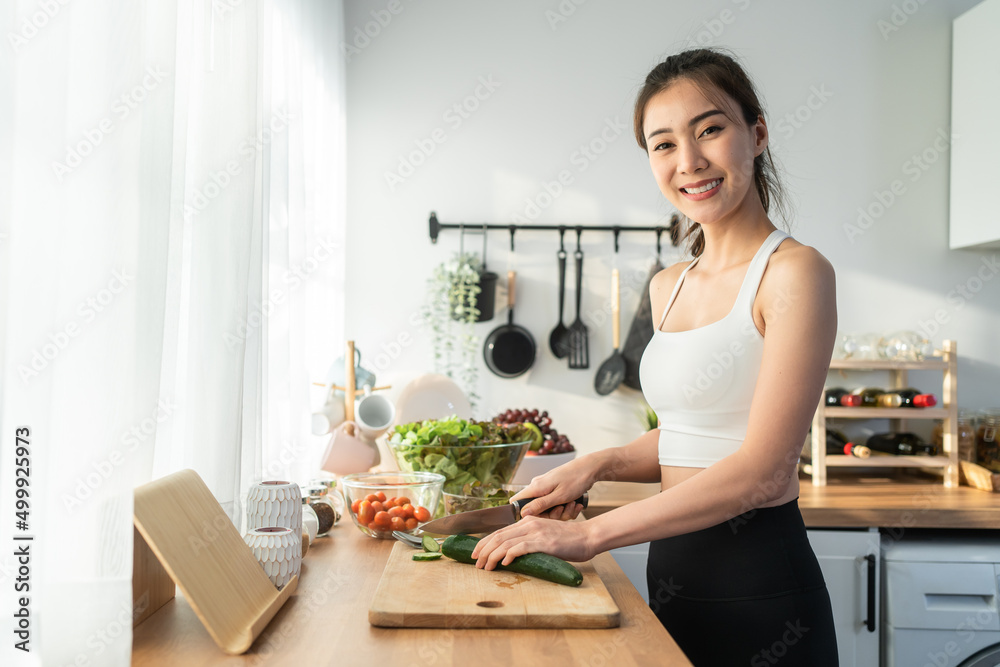 亚洲美女烹饪沙拉的肖像，看着镜头。