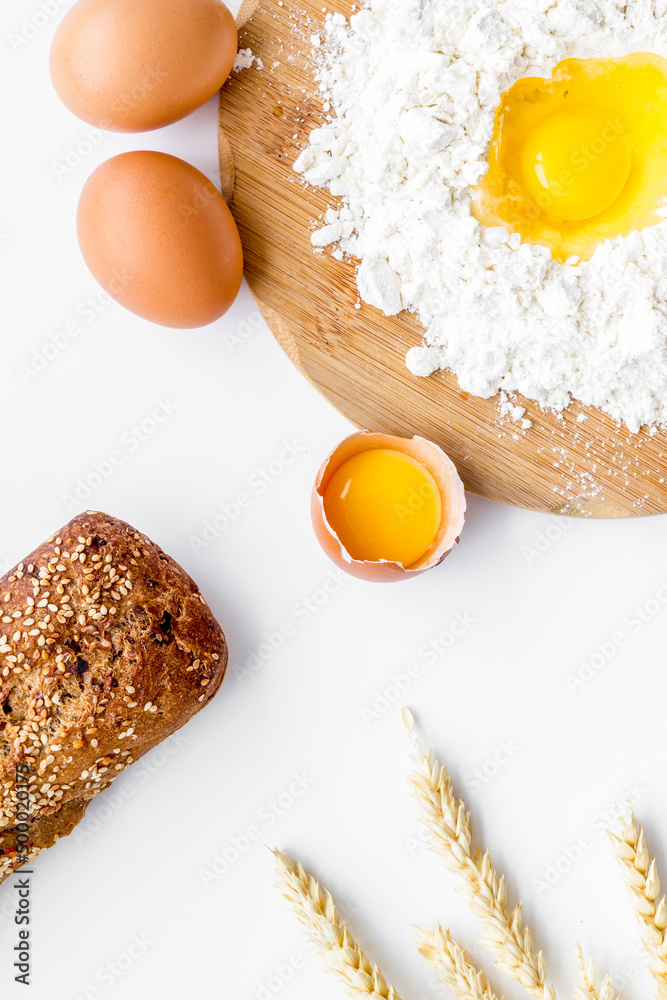 Baking background with eggs, flour and bread on white desk. Top view.