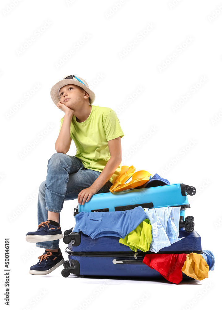 Thoughtful little boy with suitcases full of belongings on white background