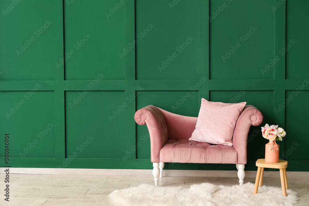 New sofa and vase with flowers on table near green wall