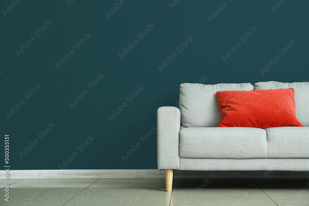 Modern sofa with pillow near color wall in room