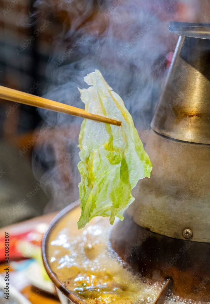 Chopsticks pick up various ingredients in the hot pot