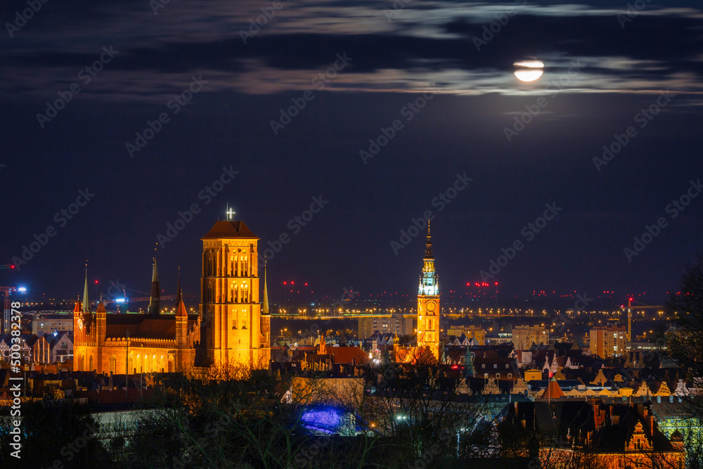 A full moon rising over the city of Gdansk at night. Poland