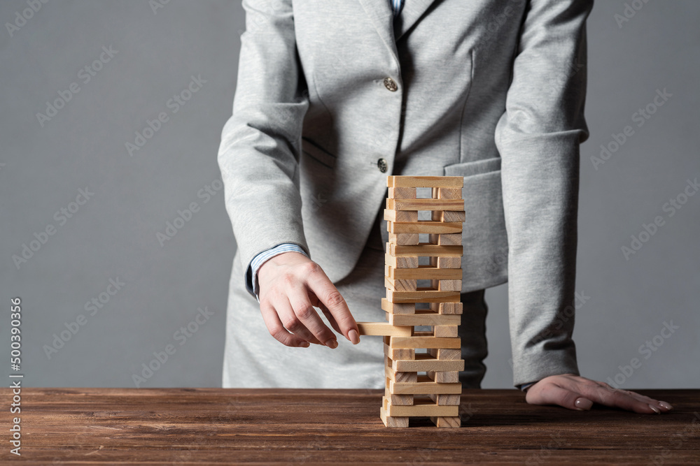 Businesswoman removing wooden block from tower