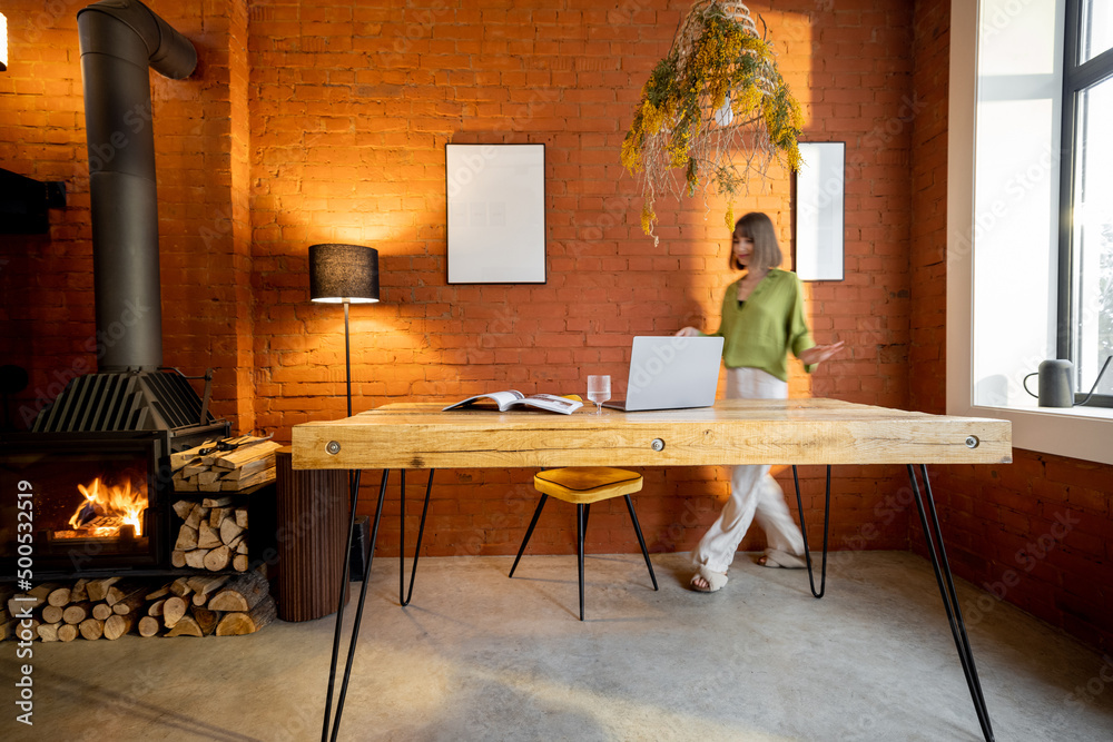 Living room interior in loft style with wooden table and burning fireplace at home. Motion blurred p