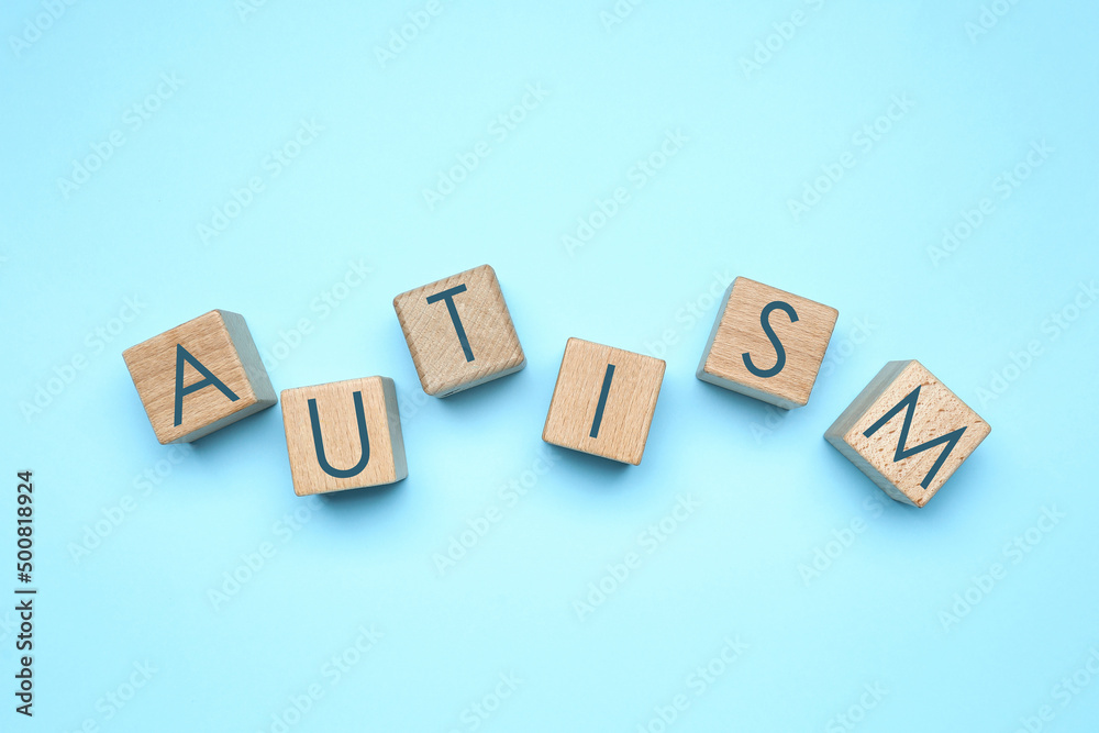 Word AUTISM made of cubes on light blue background