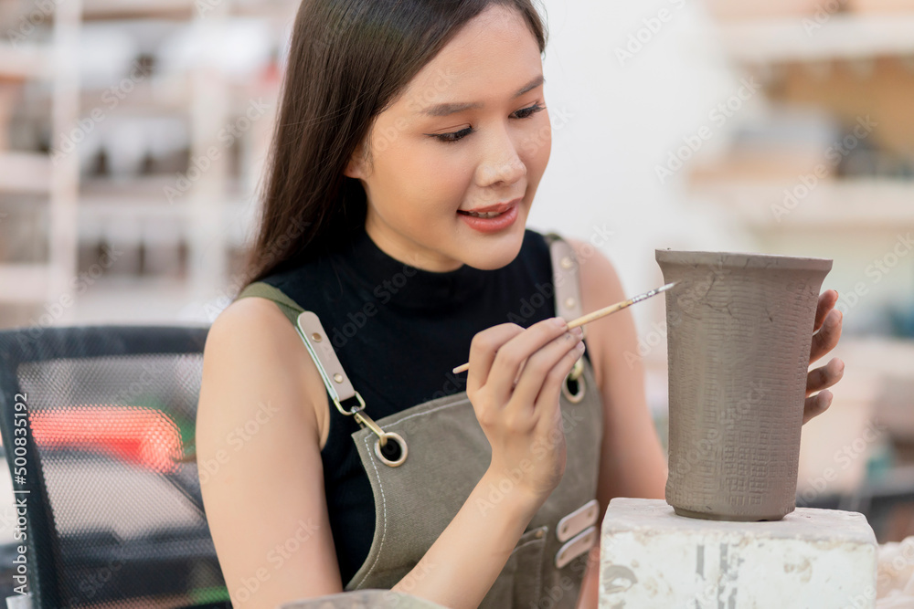 女性手在陶轮上作画的特写，亚洲女性雕塑女性涂色小