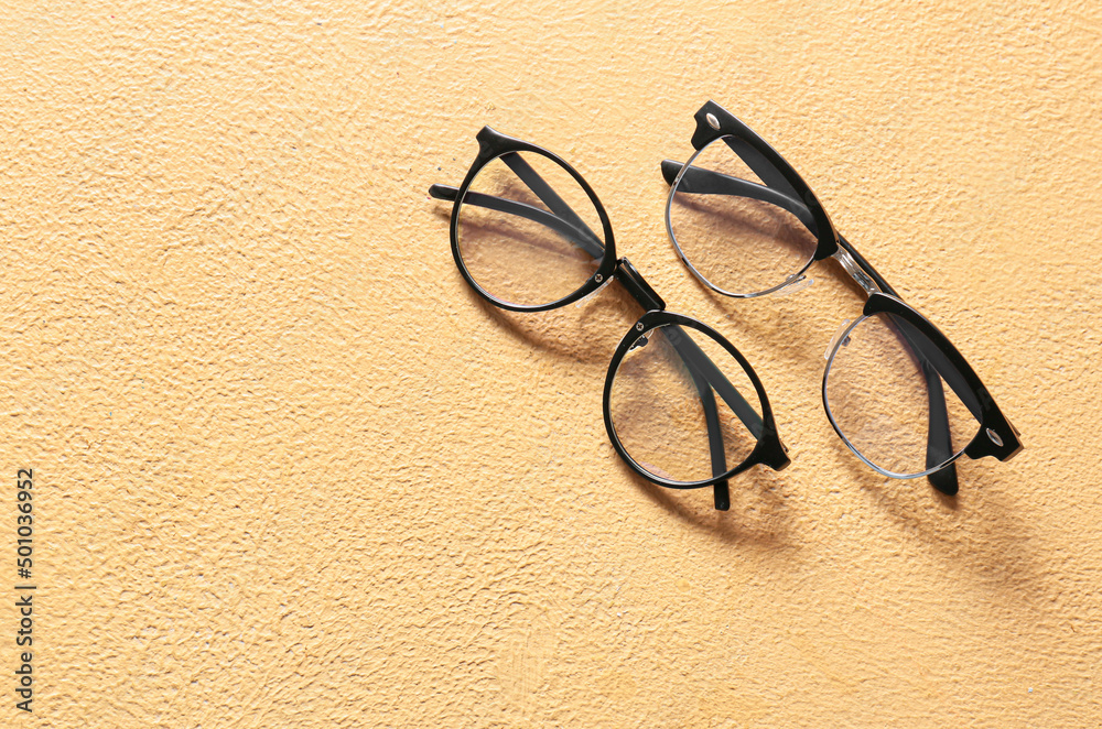 Stylish black eyeglasses on beige background