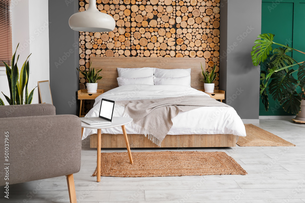 Interior of stylish bedroom with nightstands, houseplants and lamp